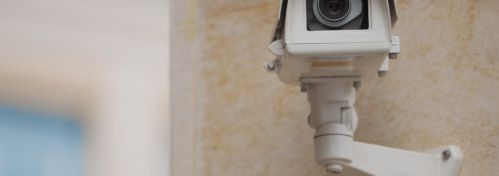 Big,White,Surveillance,Camera,On,Light,Beige,Stone,Column,Against